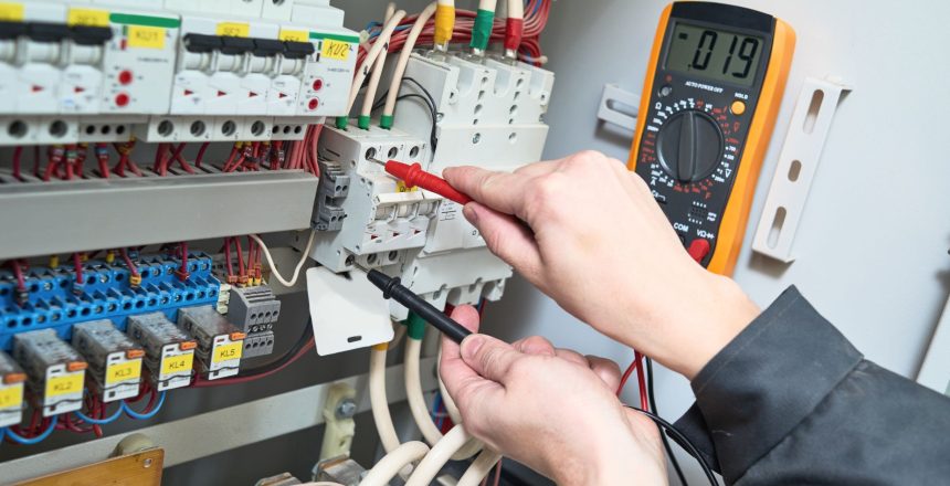 Electrician testing a consumer unit with a multimeter during an EICR