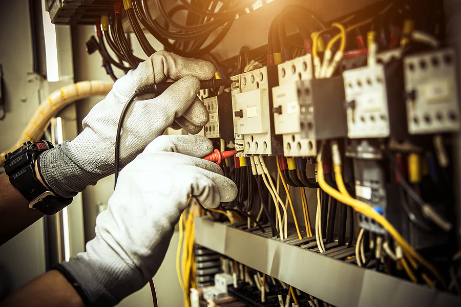 Emergency electrician wearing gloves repairing a fault in a fuse board