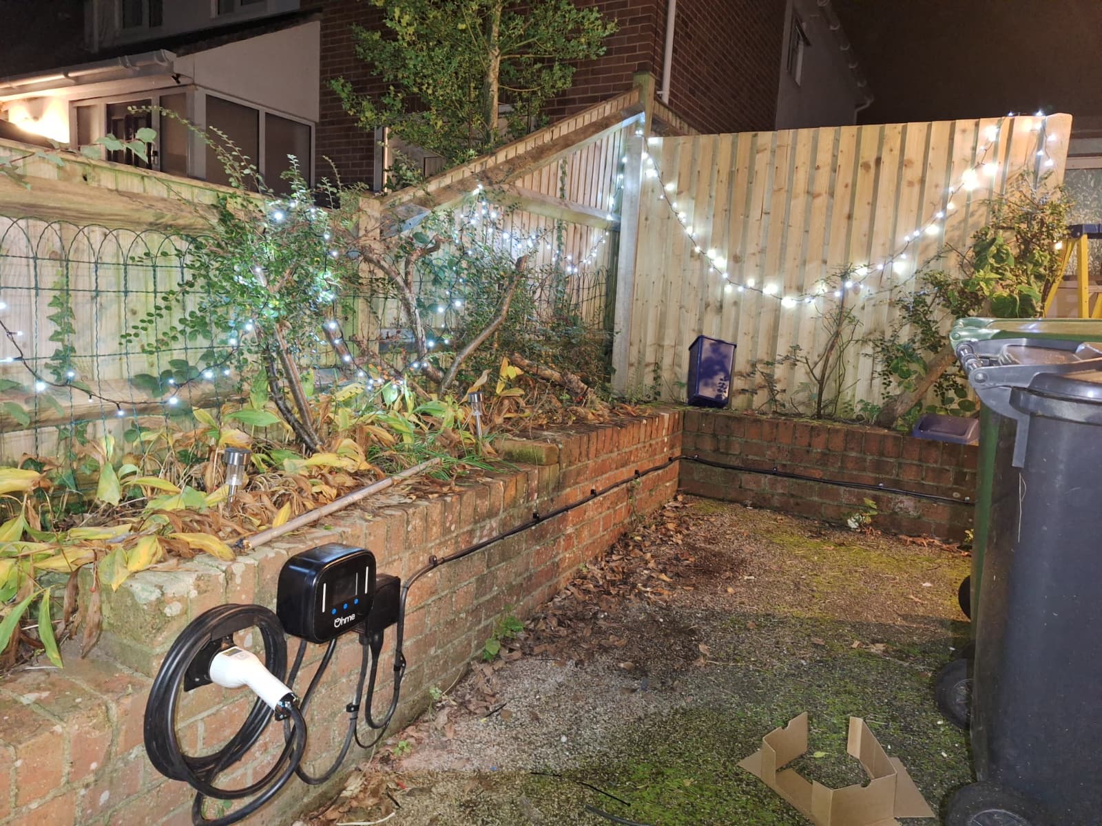 Home EV charger fitted on a garden wall